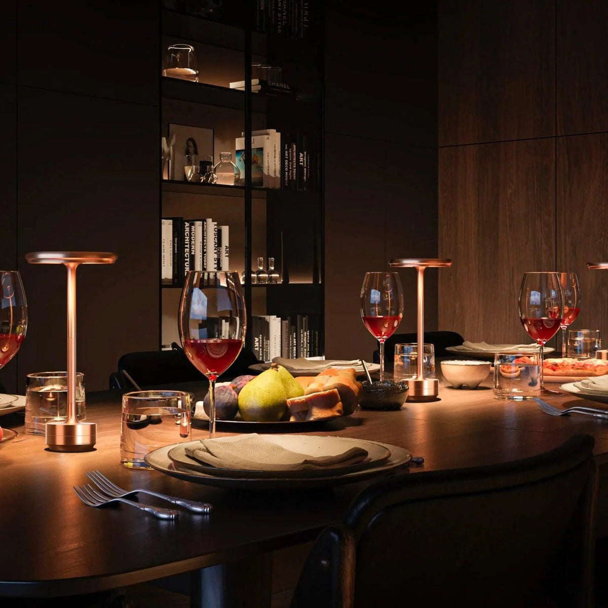 Dining table set with wine glasses, apples, and candles in a dimly lit room.